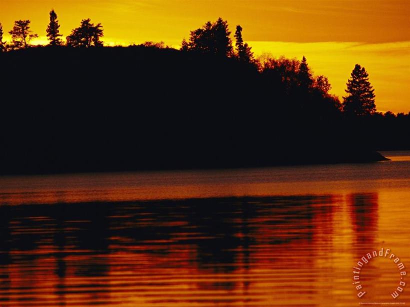 The Setting Sun Casts an Orange Glow Over Manitoba S White Lake painting - Raymond Gehman The Setting Sun Casts an Orange Glow Over Manitoba S White Lake Art Print