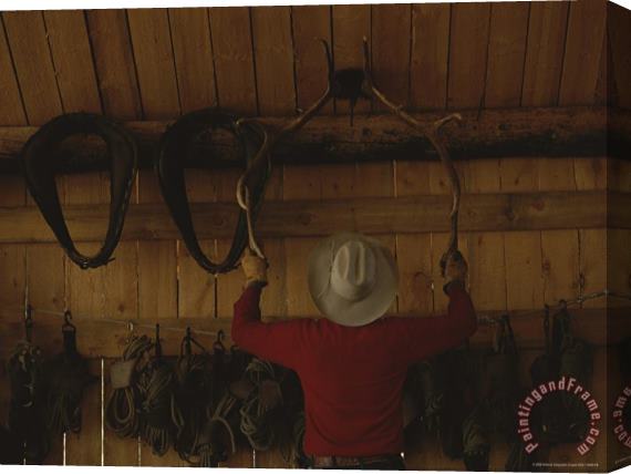Raymond Gehman An Outfitter Hangs a Set of Elk Antlers on a Cabin Wall Stretched Canvas Painting / Canvas Art